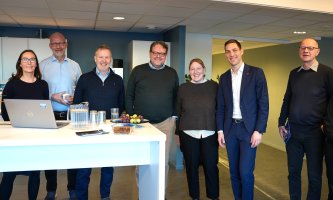 En gruppe på syv mennesker smiler mot kameraet. 