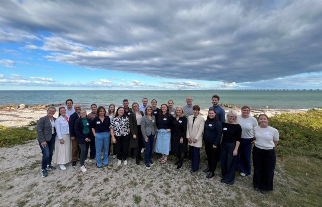 BlueActionBanos team (around 25 people) pose for a photo at the beach.