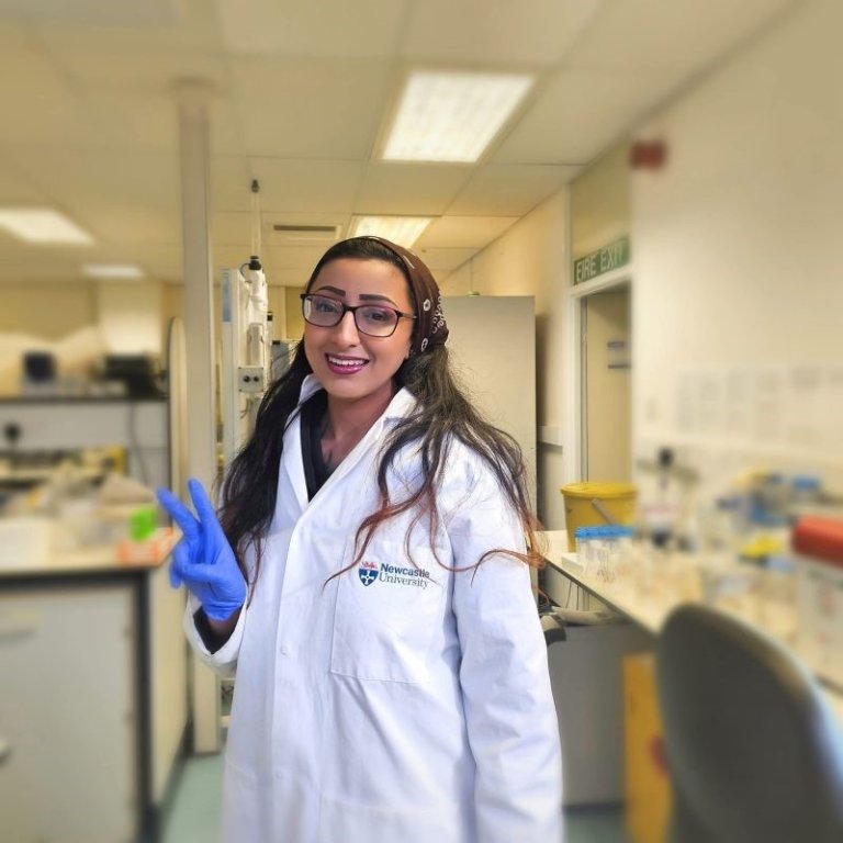 A photo of a female researcher in a lab coat in a lab