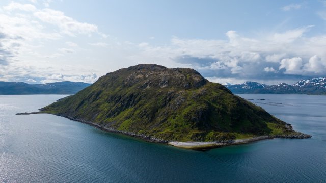 A picture of a Norwegian island surrounded by water and mountains with snow-covered peaks.