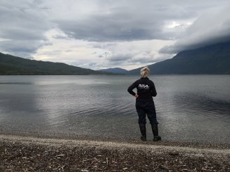 Researcher overlooking lake with clouds in the distance