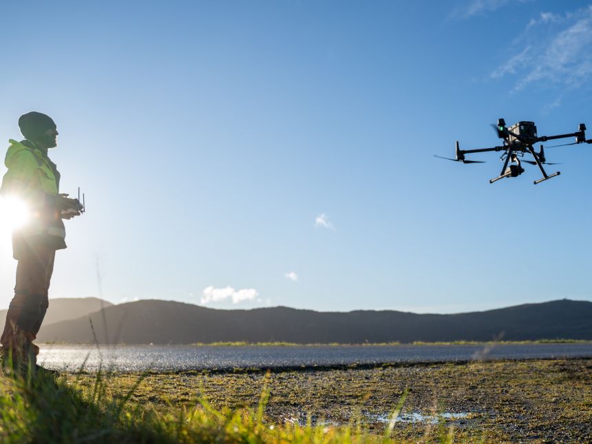 Man steers a large drone with a remote bye the coast