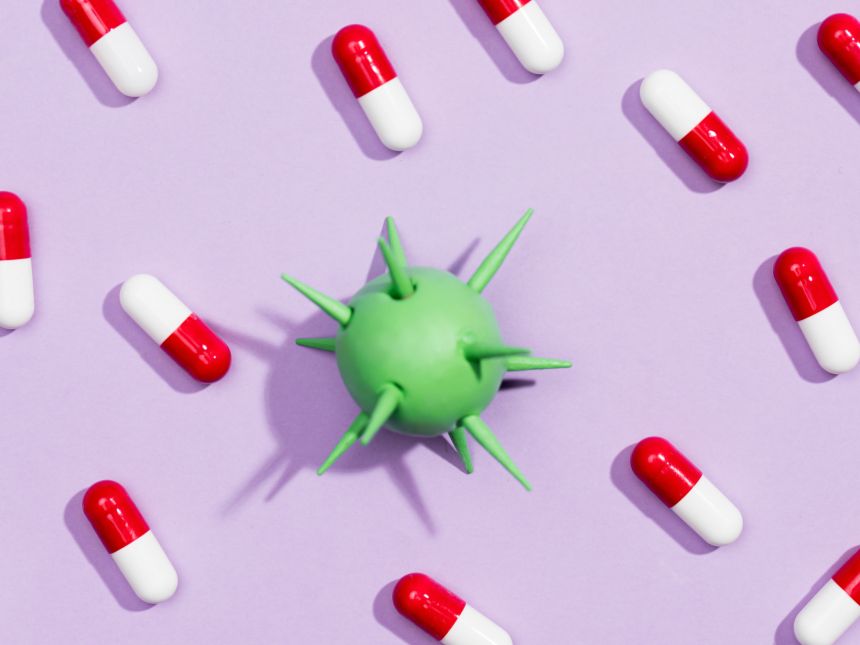 Red and white pills and green AMR in the shape of green ball with spikes