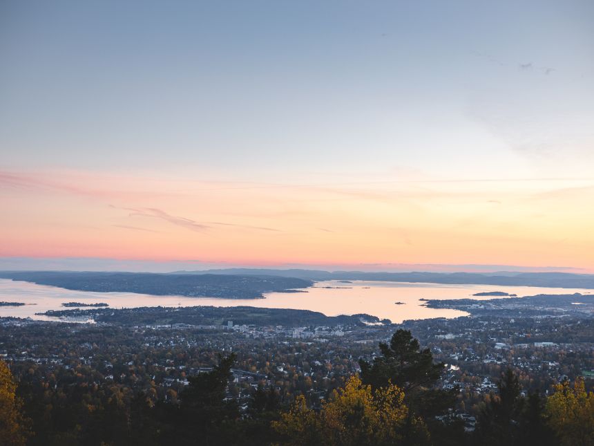 Sunset from Vettakolltoppen paints Oslofjord in soft pastels, offering a serene panorama above the city.
