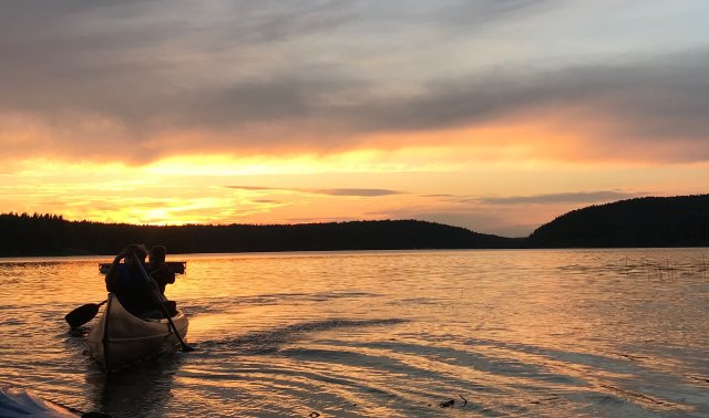 To personer padler kano i solnedgang