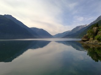 Bilde av fjord med fjell og stille vann. 
